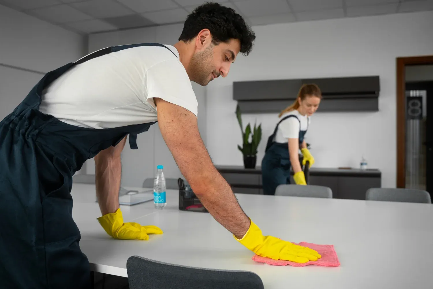 Experienced janitorial staff disinfecting a conference room table