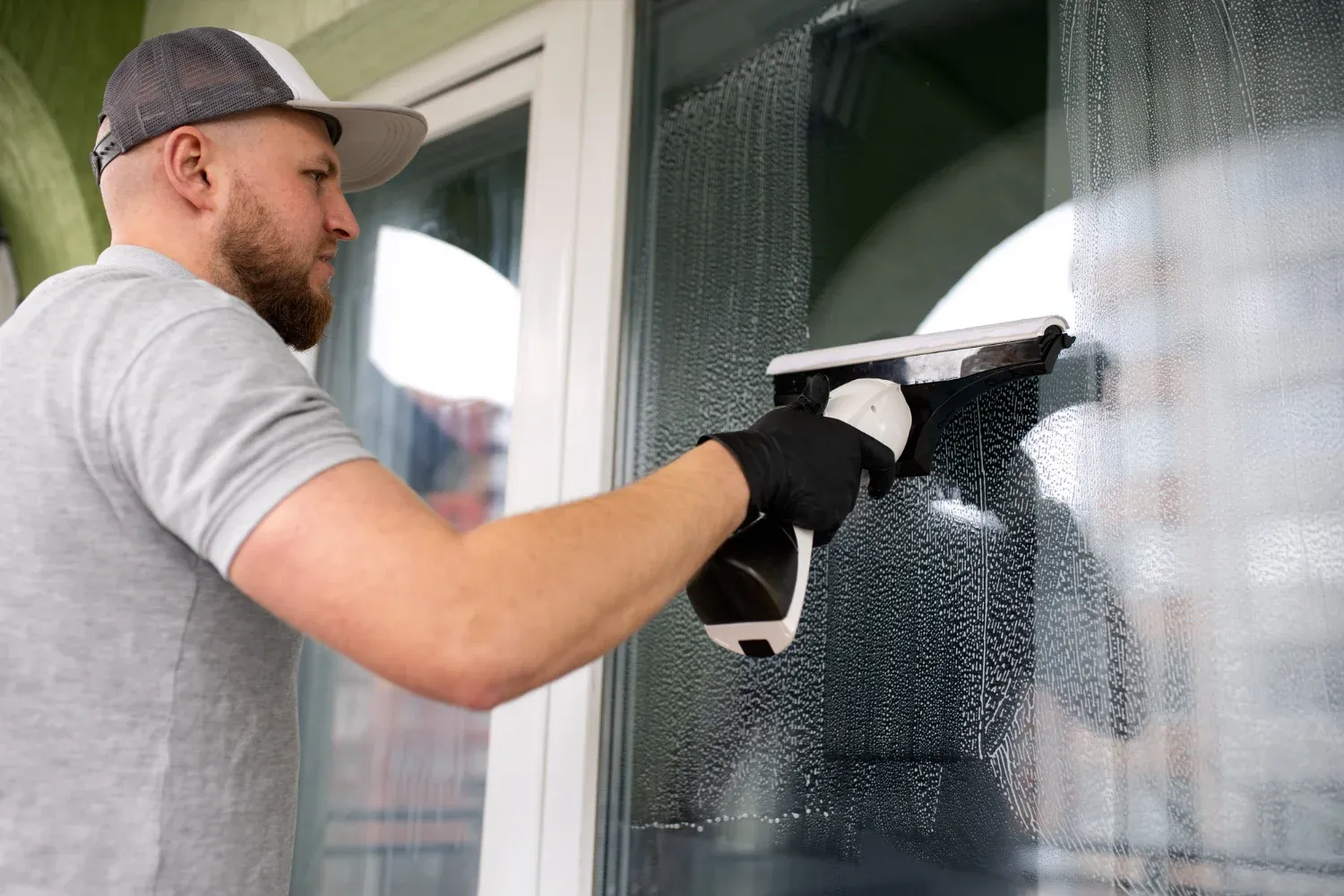 Professional cleaner using eco-friendly products on residential windows in Boston.