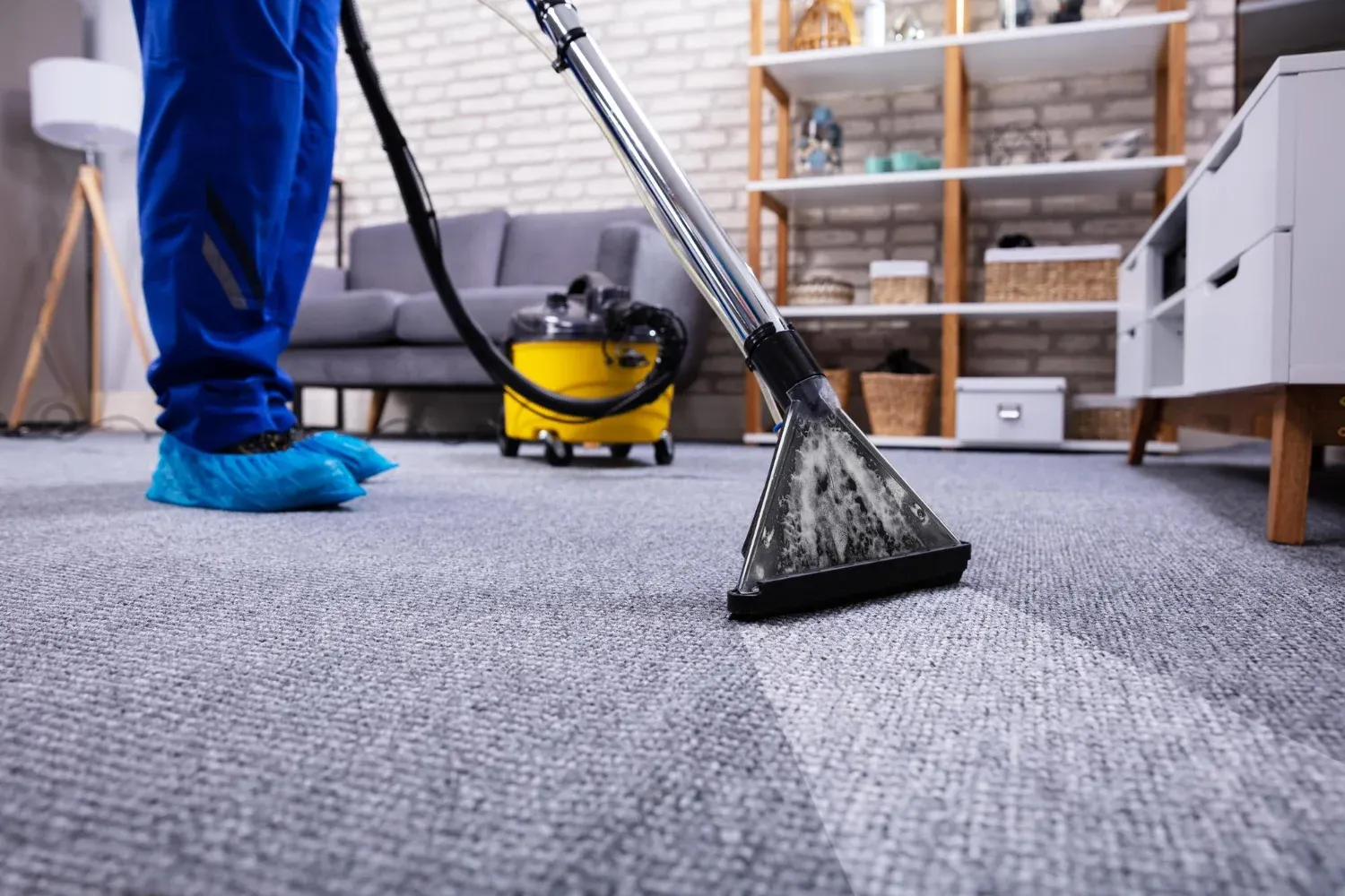 Close-up of a technician treating a coffee stain on a high-traffic carpet in an office using a specialized stain remover.